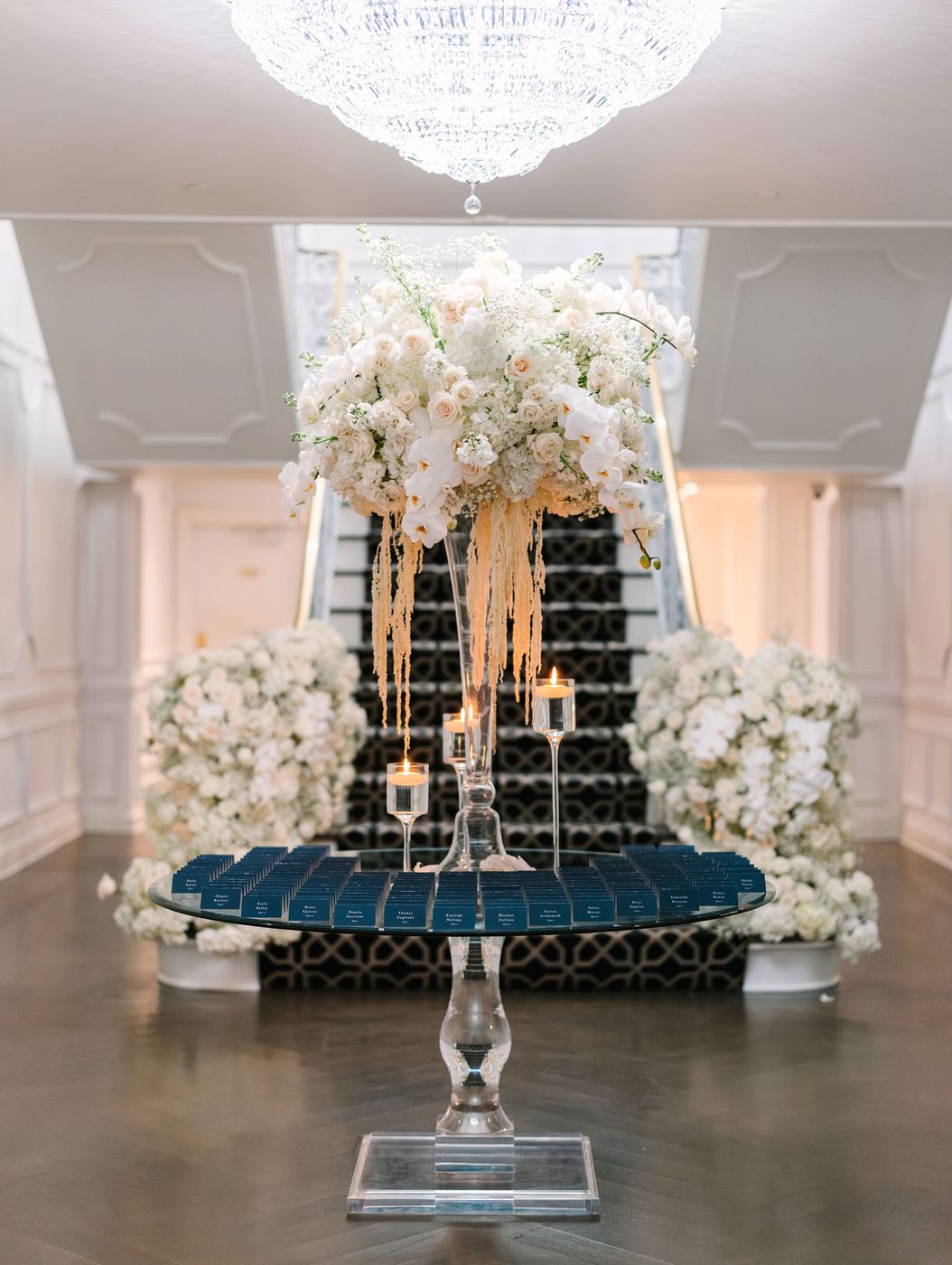 Seating card display at the foot of a staircase framed in white flowers