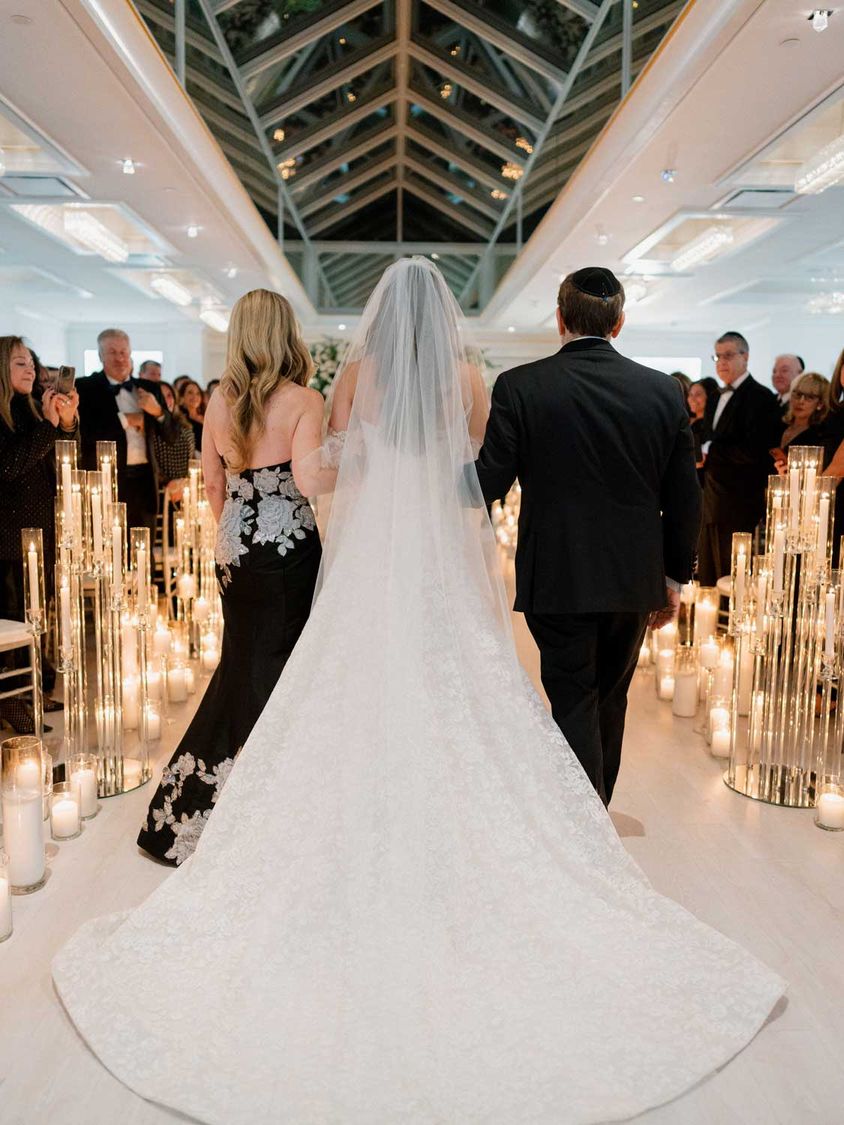 Bride walking down a candlelit aisle under a glass ceiling