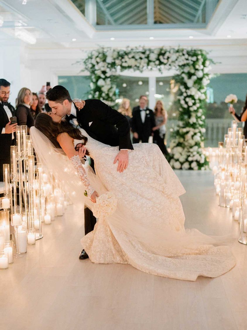 Couple sharing a dip kiss at the end of the aisle