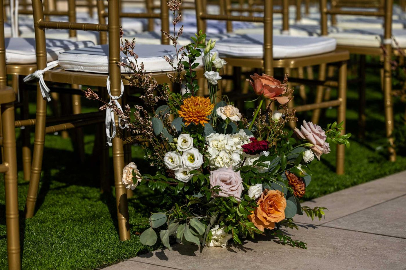Low arrangement of peach and white flowers along the ceremony aisle
