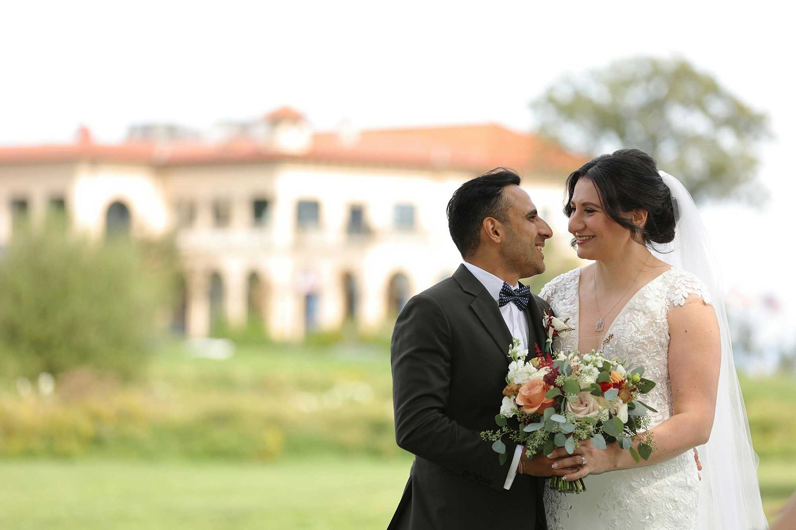 Bride and groom smiling at each other, her bouquet in autumn colors