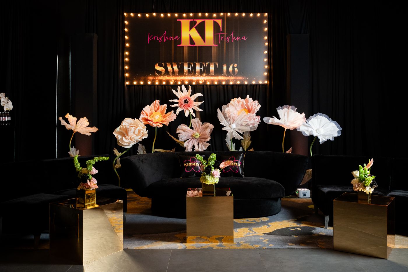 Sweet 16 lounge with black velvet seating and oversized paper flowers