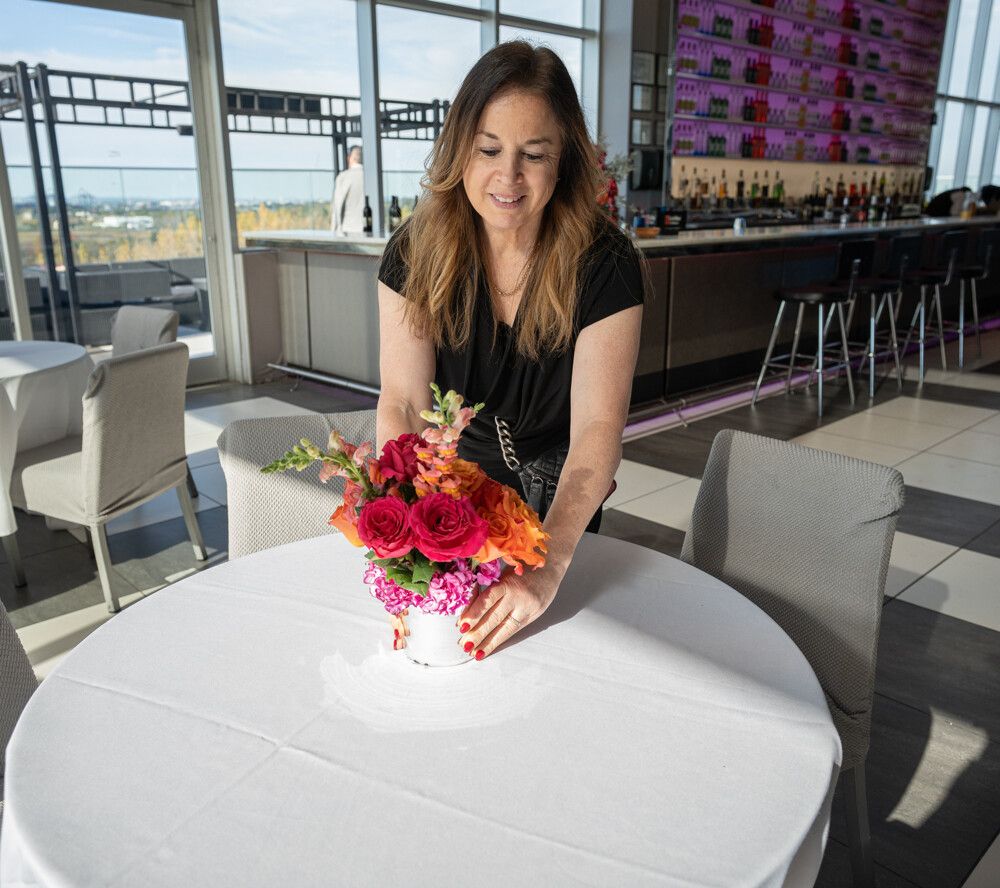 Lisa Ivler adjusting a floral centerpiece in a bright reception room