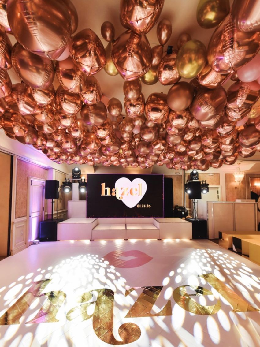 Bat mitzvah room under a ceiling of rose-gold balloons