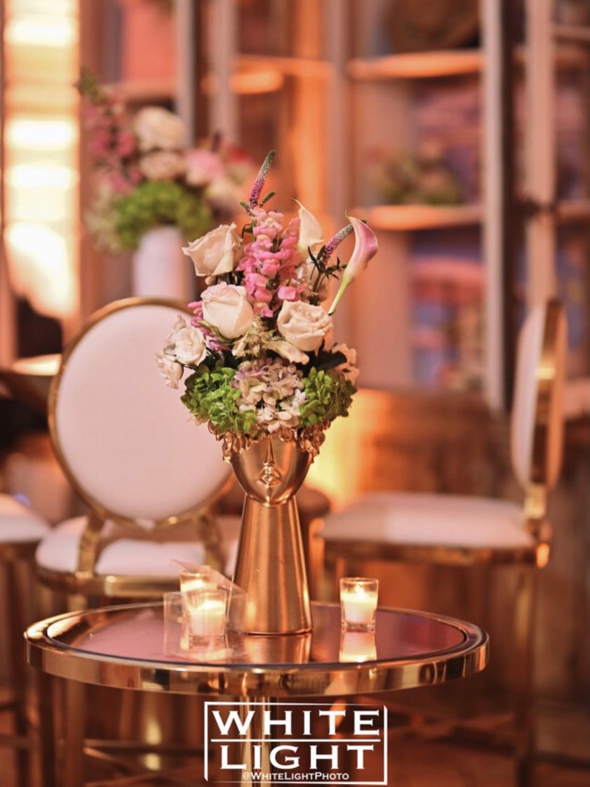 Gold table with a pink rose arrangement and candles