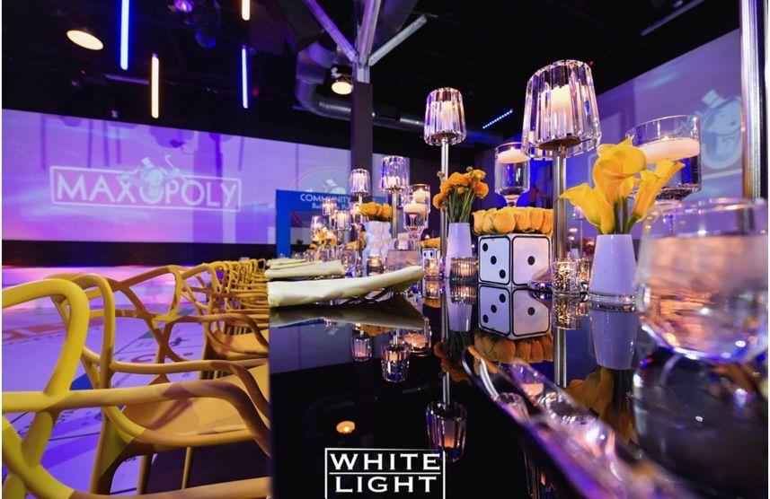 Long table with yellow flowers, candles and dice in a room lit purple