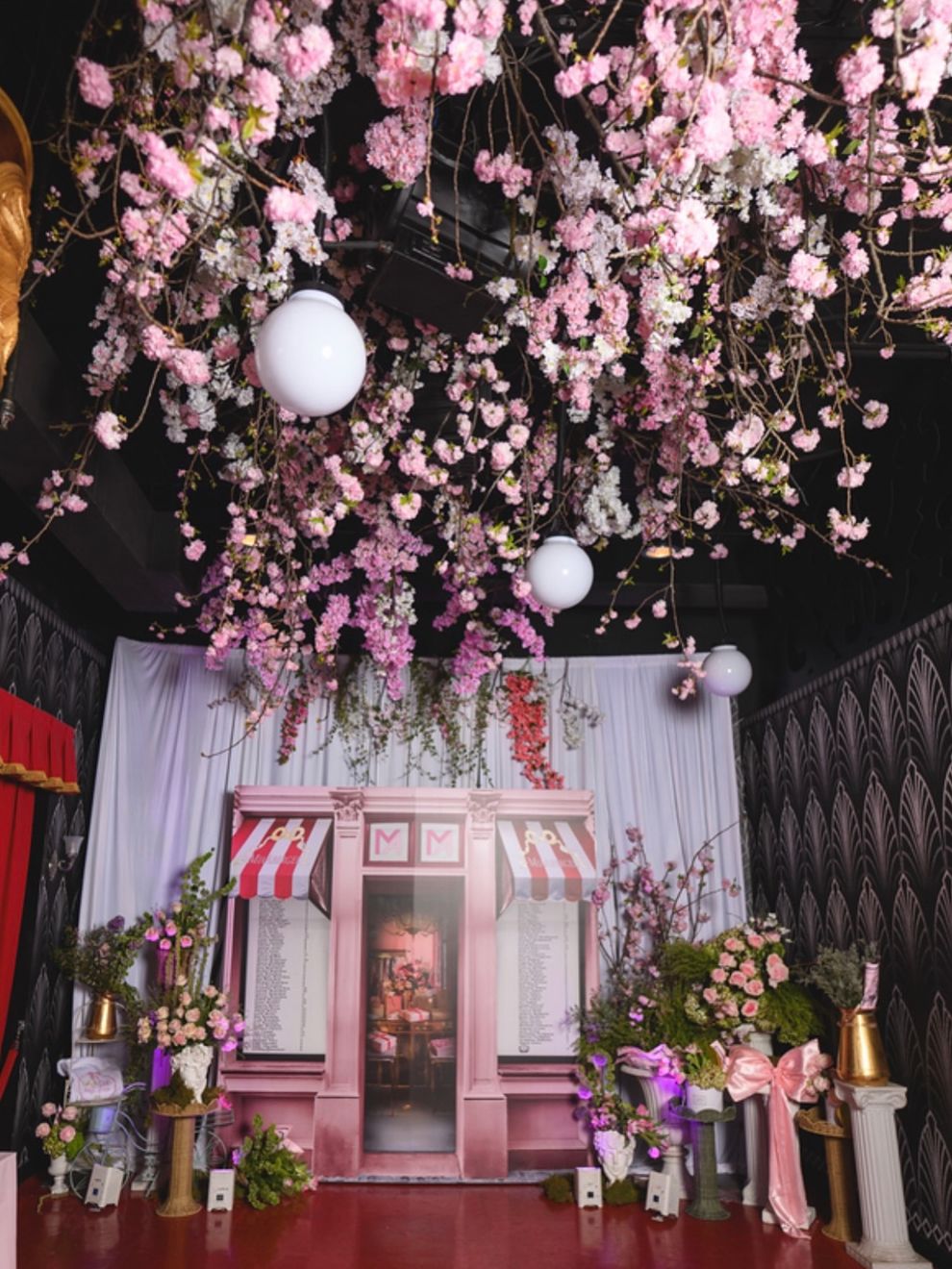 Ceiling of pink blossoms over a pink storefront backdrop