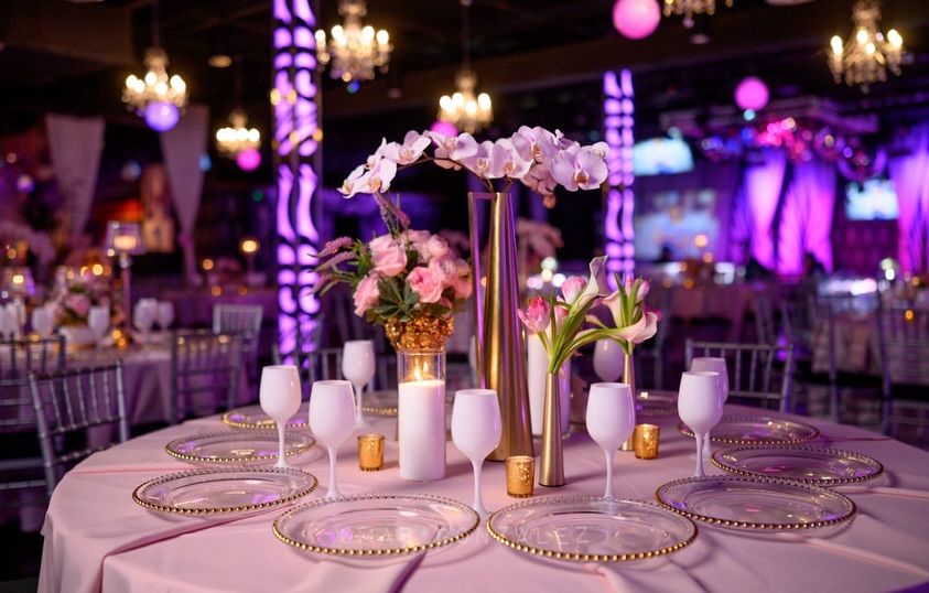 Round table with white orchids, pink roses and gold-rimmed plates