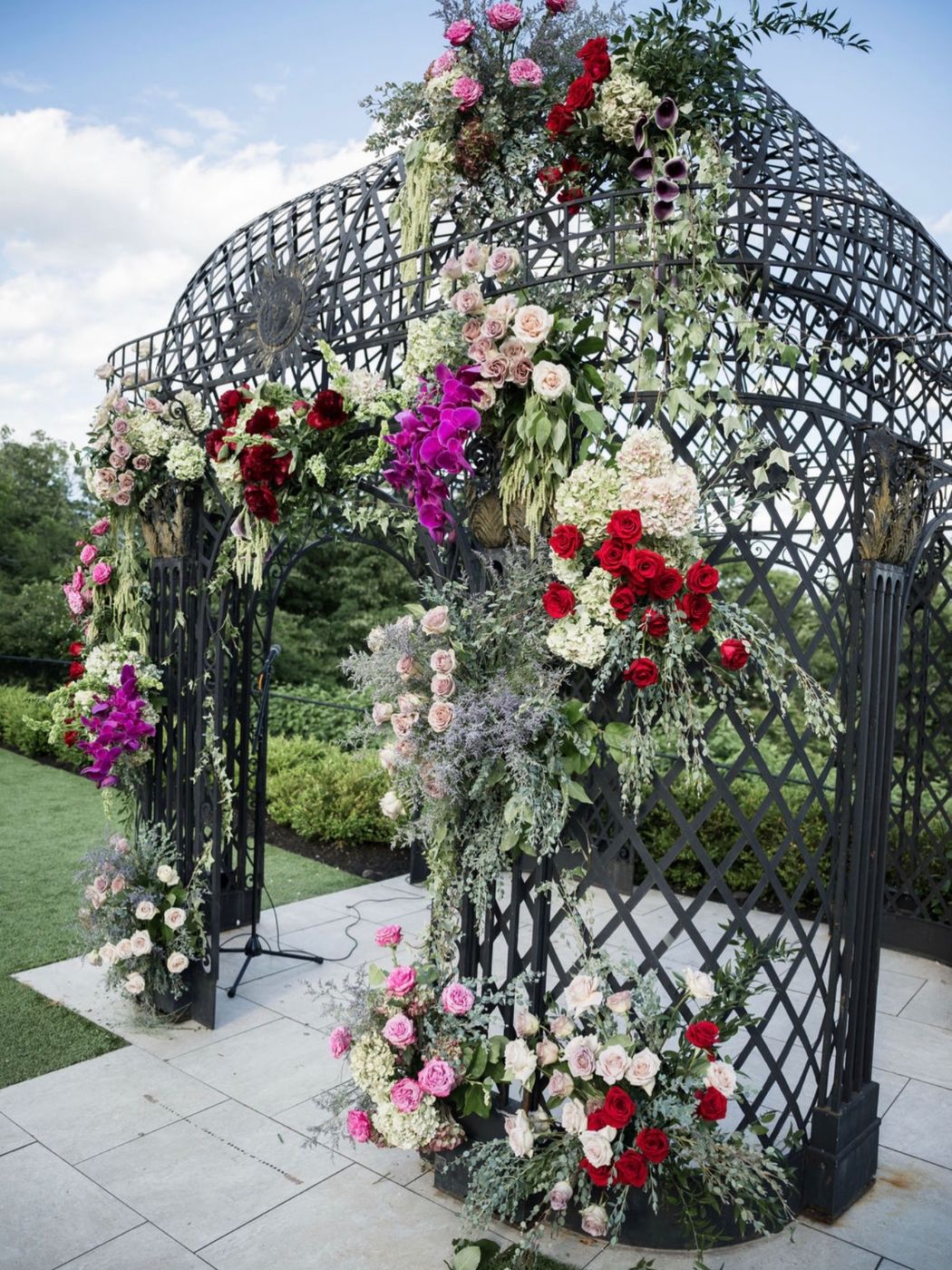 Wrought-iron gazebo covered in red and pink flowers
