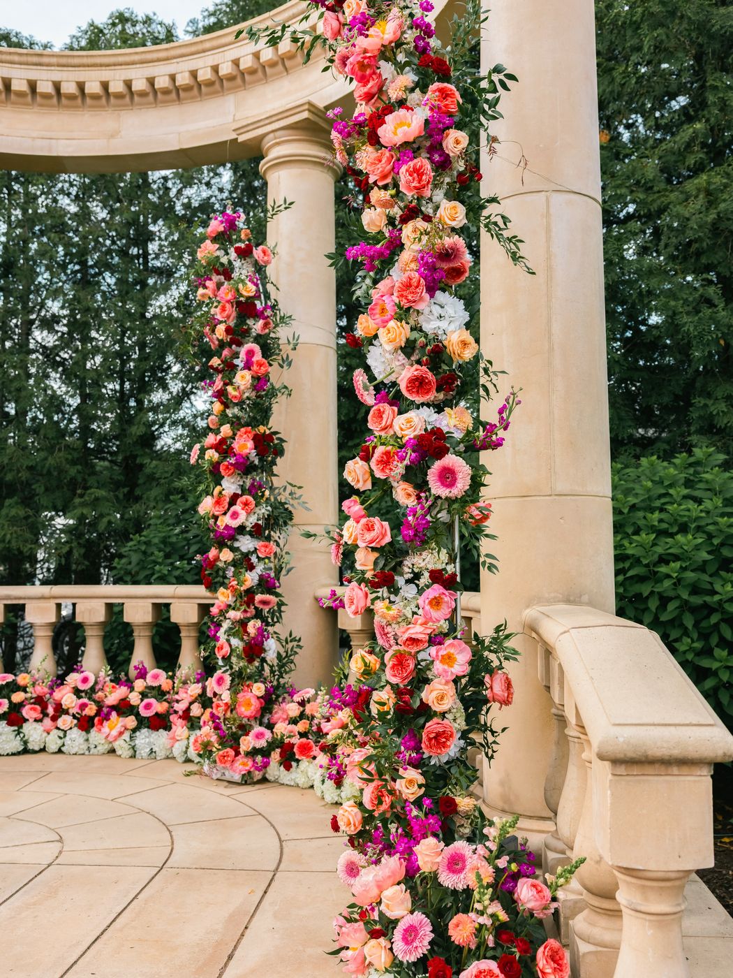 Column wrapped in coral and pink roses at an outdoor ceremony