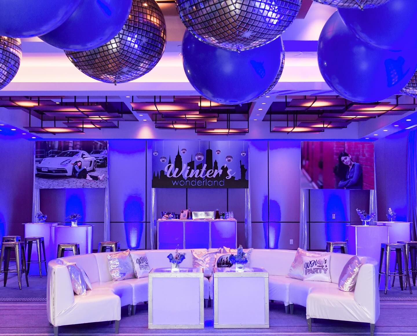 Bat mitzvah lounge with white sofas under blue balloons and mirrored spheres