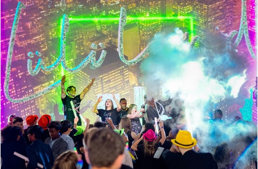 Teens dancing in haze under a neon sign