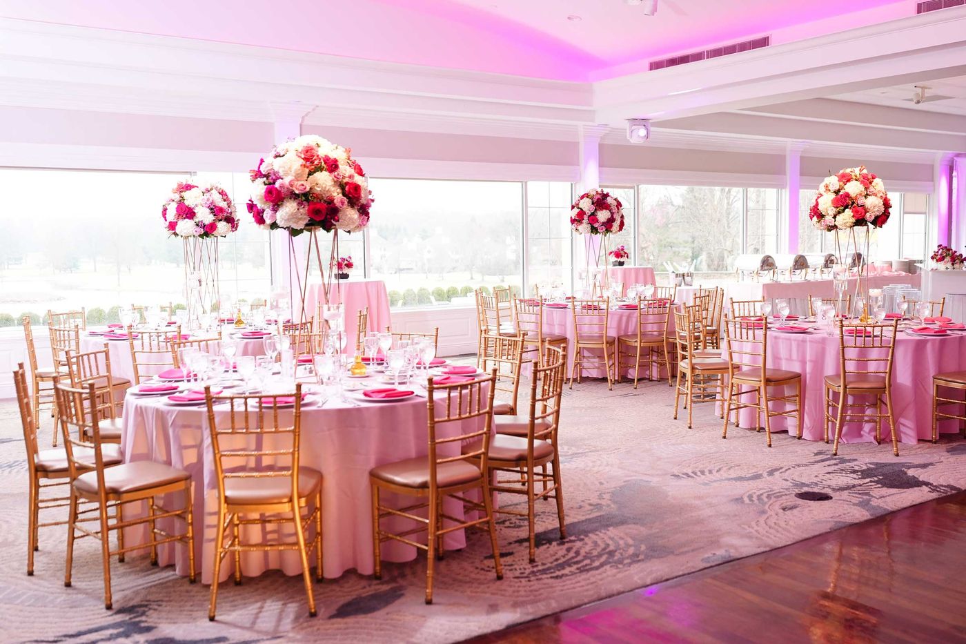 Round tables with tall red and pink centerpieces beside the dance floor