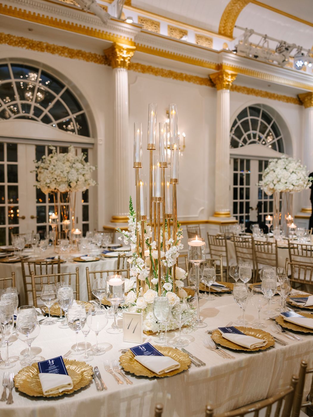 Reception tables with tall gold candelabras and white flowers