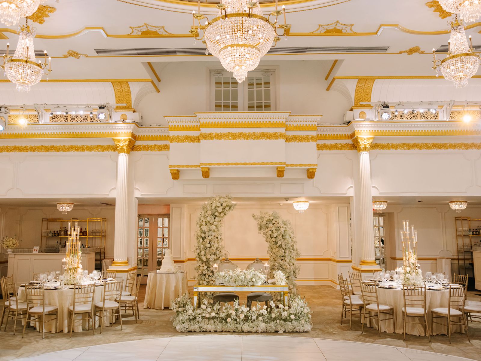 Gold ballroom with crystal chandeliers, a floral sweetheart table and round tables