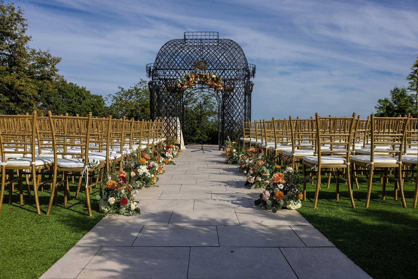 Ceremony aisle on a lawn leading to a garden gazebo