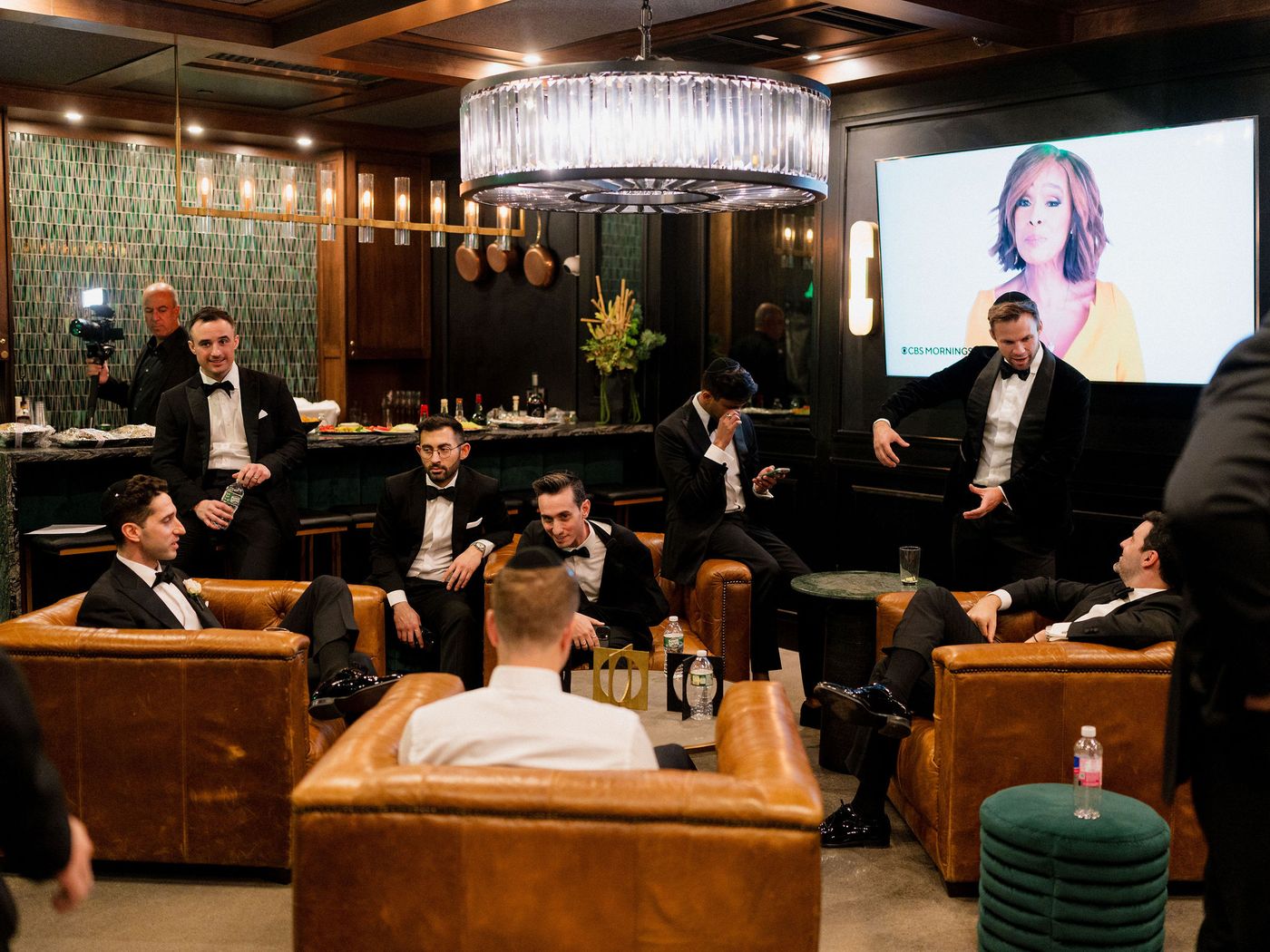 The groom and his wedding party in a leather-chair lounge under a crystal chandelier