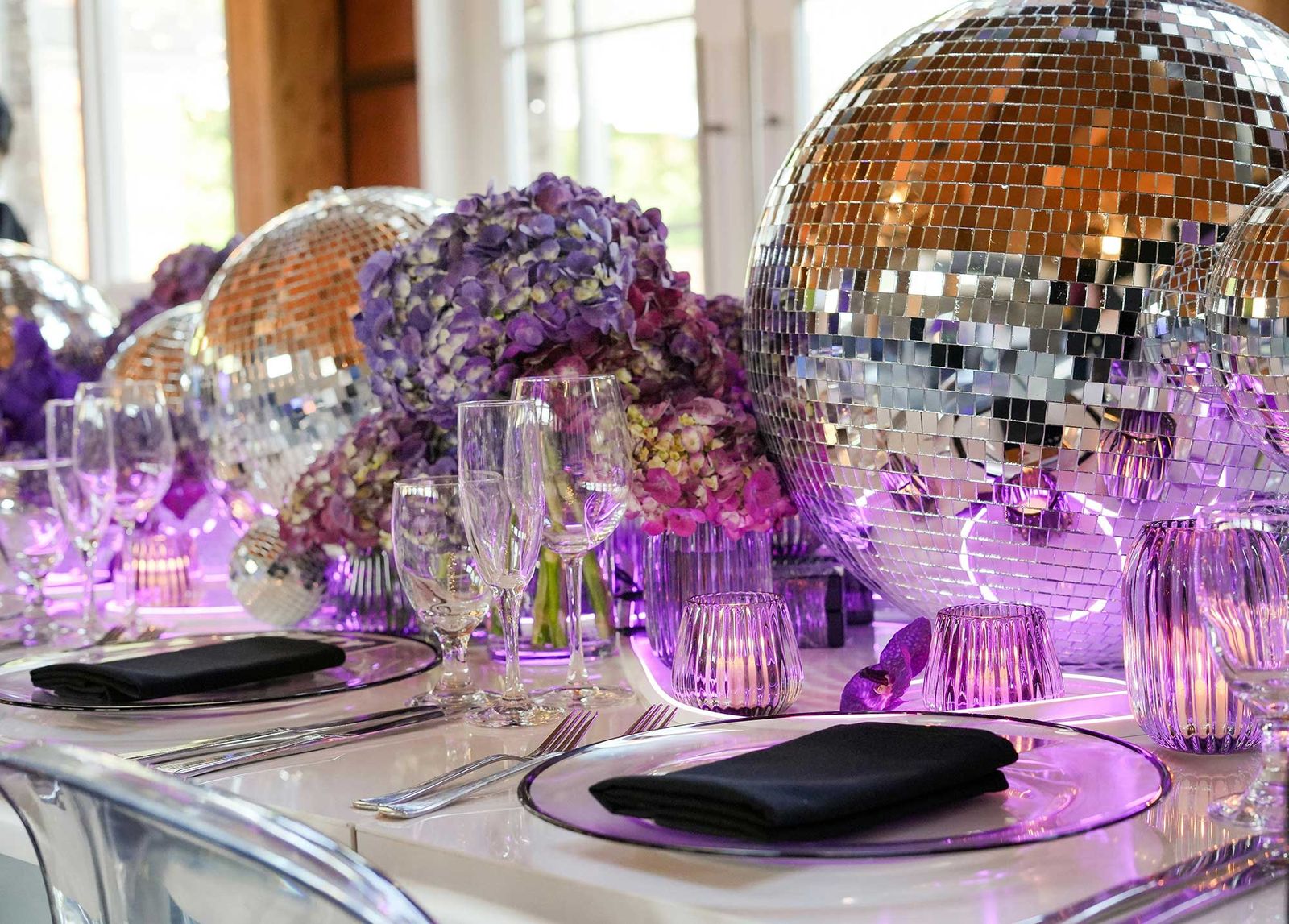Dinner tables with purple florals and mirrored disco balls