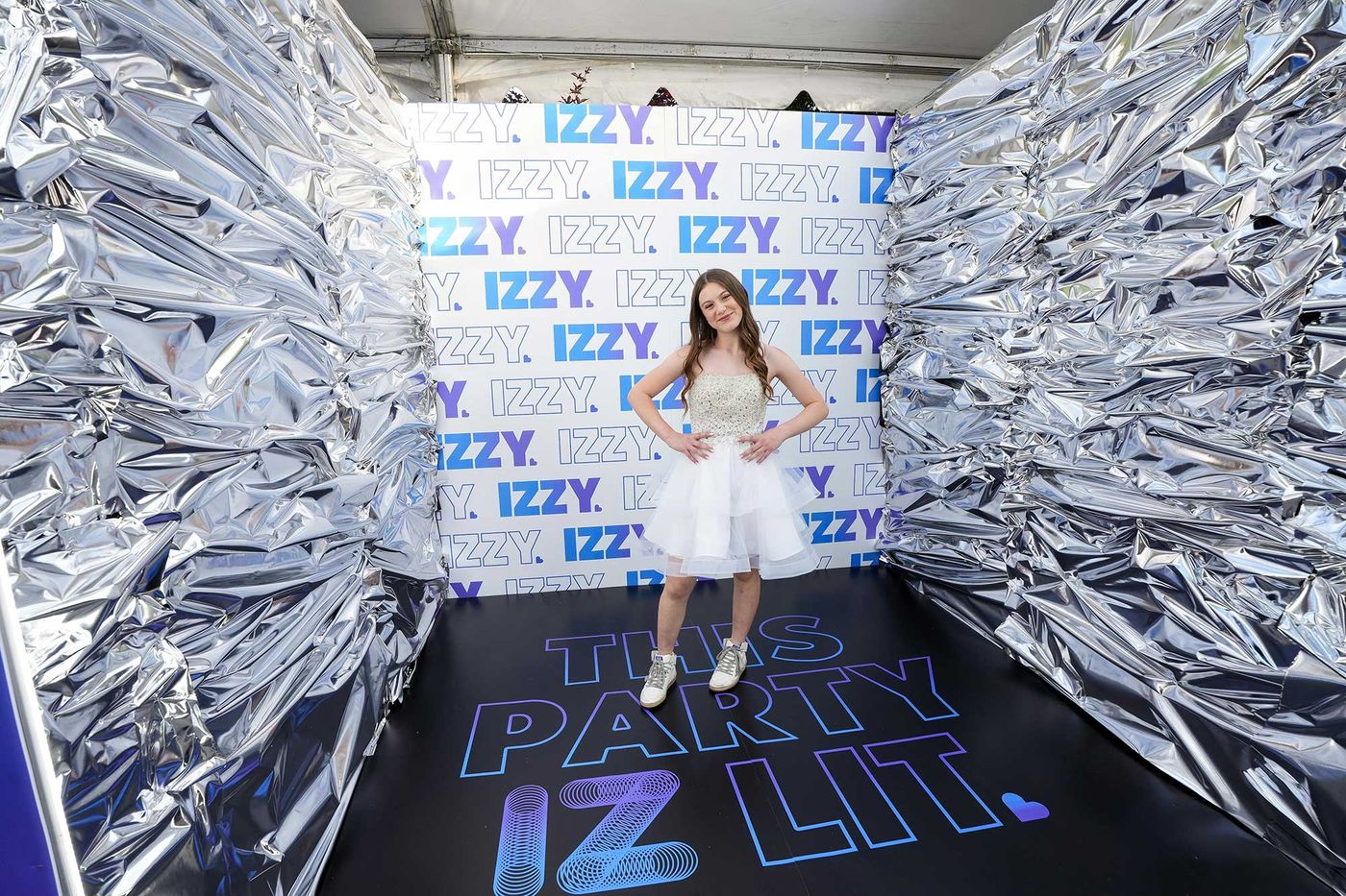 Guest posing inside a silver photo booth printed with the bat mitzvah logo