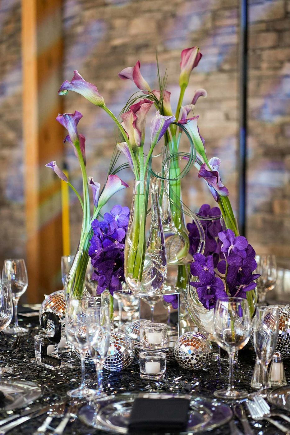 Centerpiece of purple calla lilies and orchids in tall glass