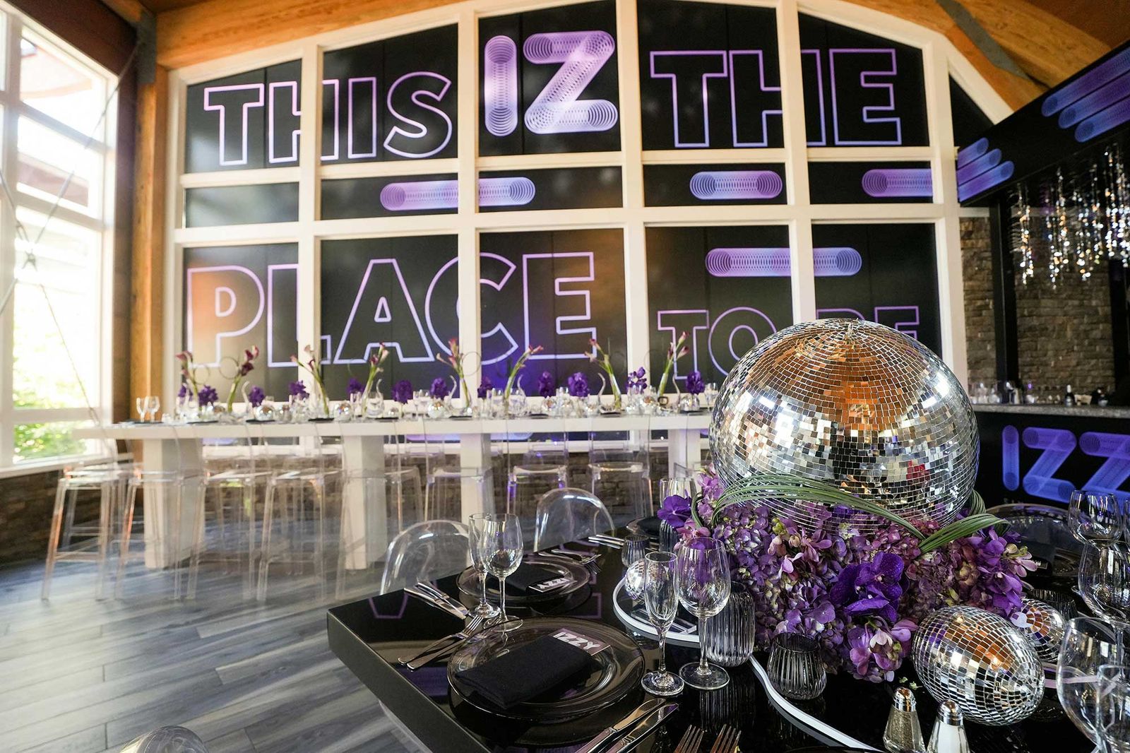 Long table set with silver and purple under a custom window graphic