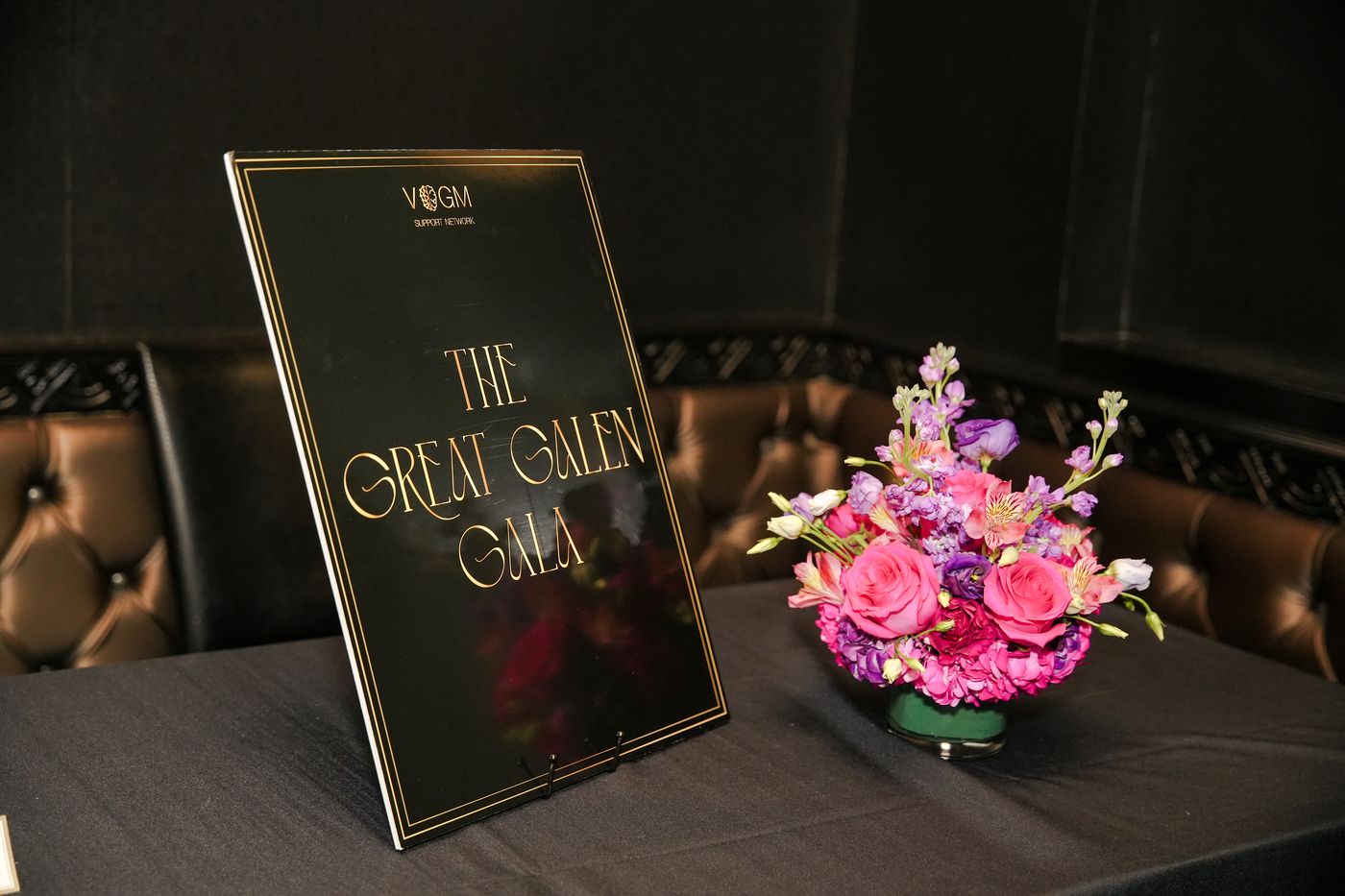 The Great Galen Gala sign beside a low arrangement of pink roses