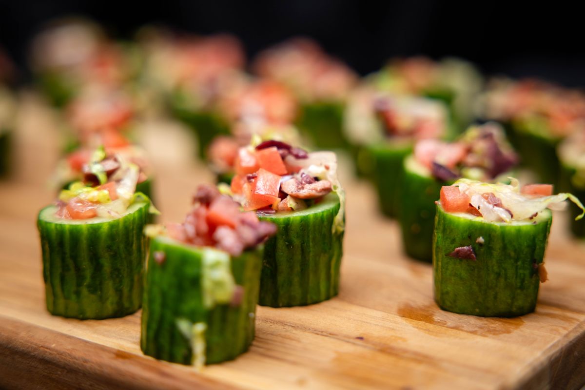 Cucumber cups filled with chopped salad on a wooden board