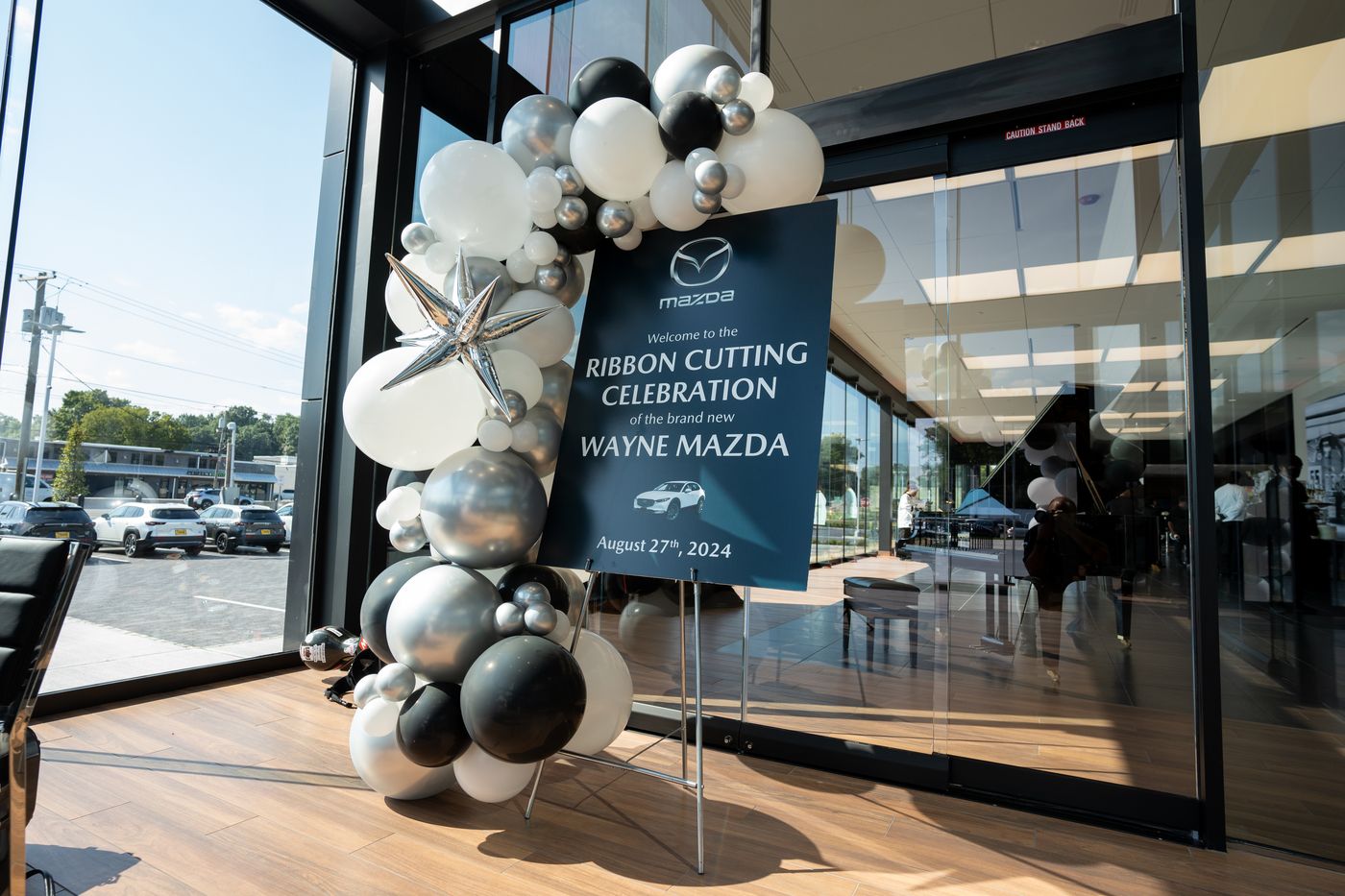 Silver and black balloon installation framing a ribbon-cutting sign