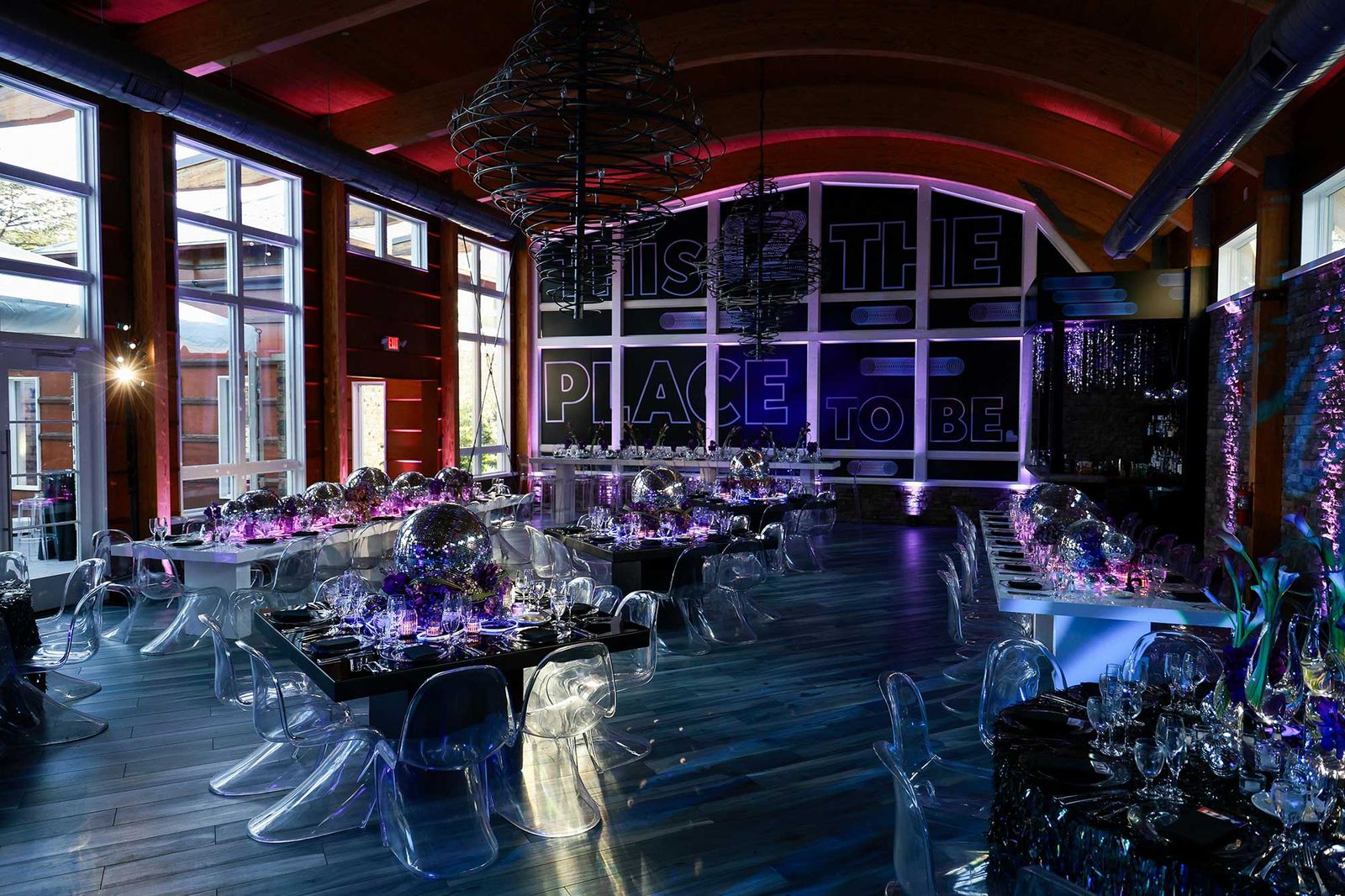 Room with clear chairs and purple-lit tables in front of a custom window graphic